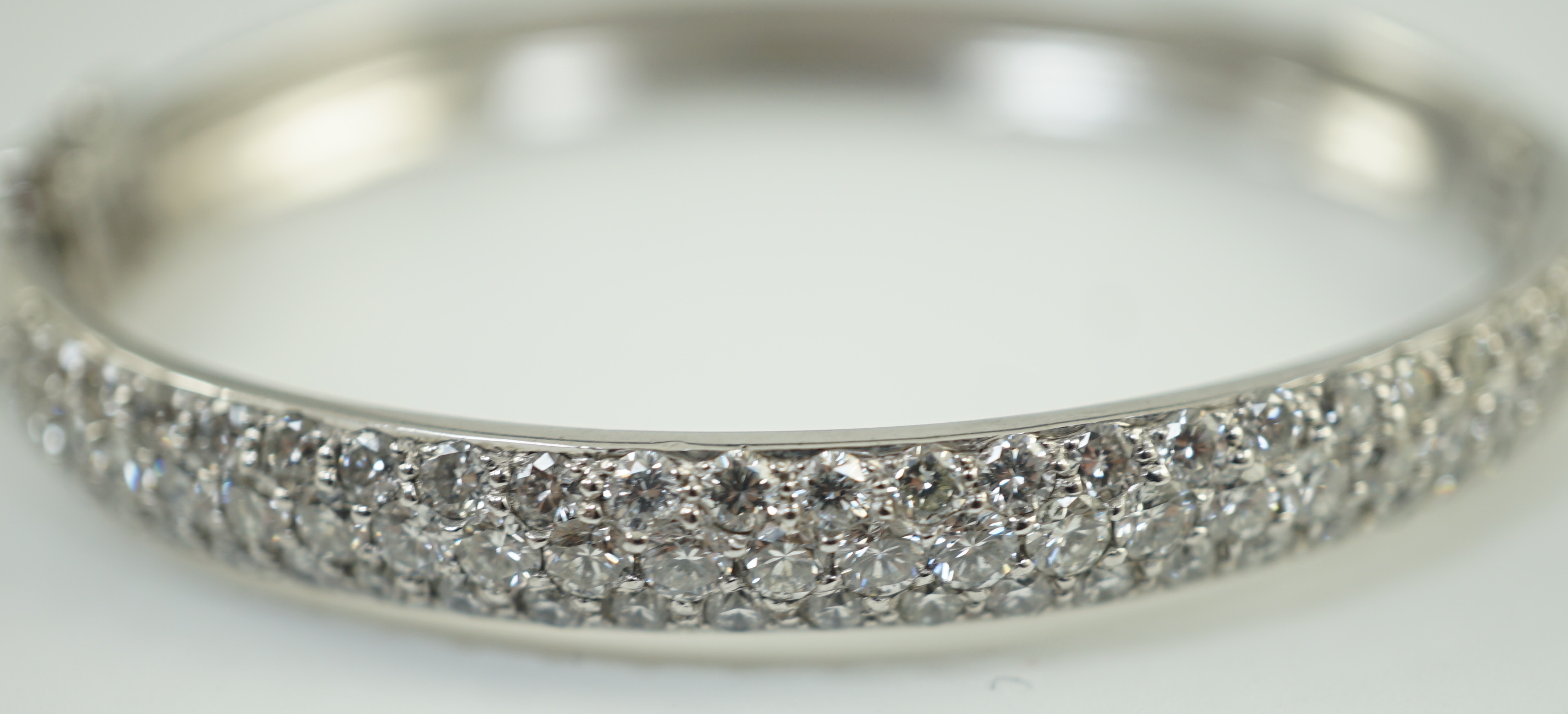 A modern 18ct white gold and pave set diamond hinged bangle